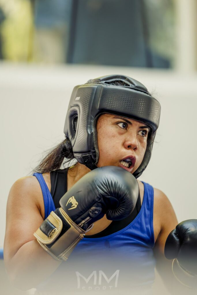 Une combattante en garde, casque et gants noirs